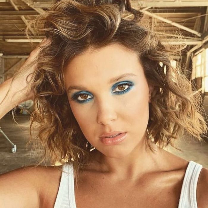 Millie Bobby Brown con el cabello teñido de rubio y un maquillaje en tonos turquesa