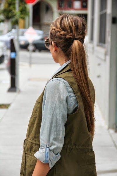 Chica de espaldas con chaleco verde militar y camisa azul cielo, peinado con coleta alta y media trenza lateral