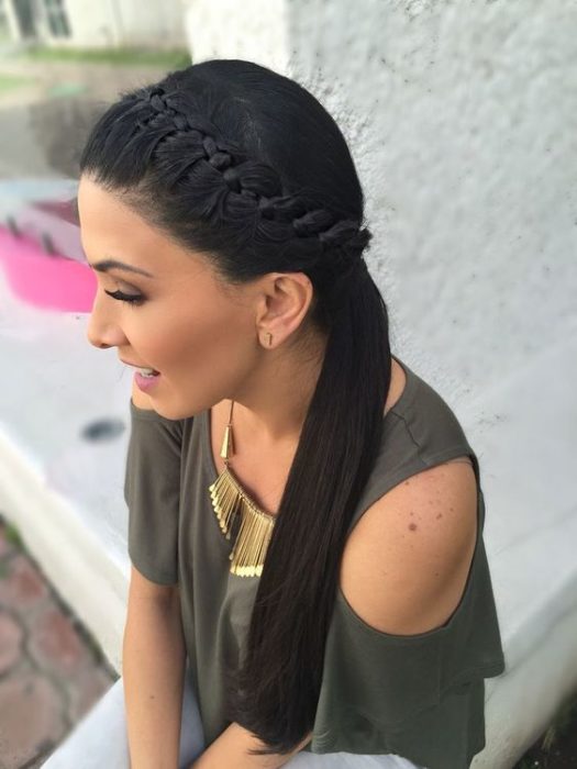 Chica sentada en la orilla de un escalón, posando de lado, mostrando un peinado de coleta con trenza lateral de diadema