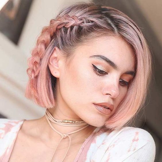 Chica de cabello corto teñido en rosa palo, posando de lado y mostrando un peinado de trenza lateral