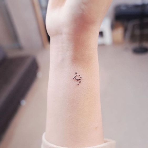 Tatuaje pequeño de planeta en la muñeca