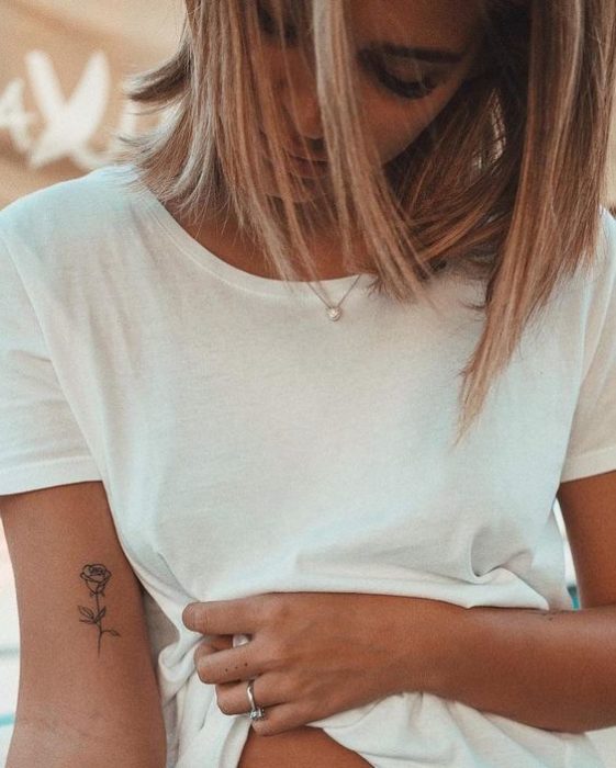 Tatuaje de rosa con tinta negra en la parte interior del brazo