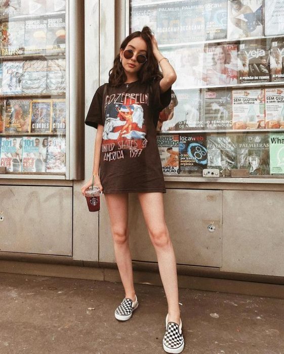 Chica con look grunge usando blusa negra y Vans blancas de cuadros