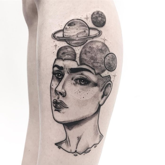 Tatuaje de la cabeza de una mujer con planetas saliendo de su cráneo