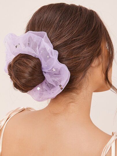 Chica de cabello castaño con chongo bajo y un scrunchie lila gigante