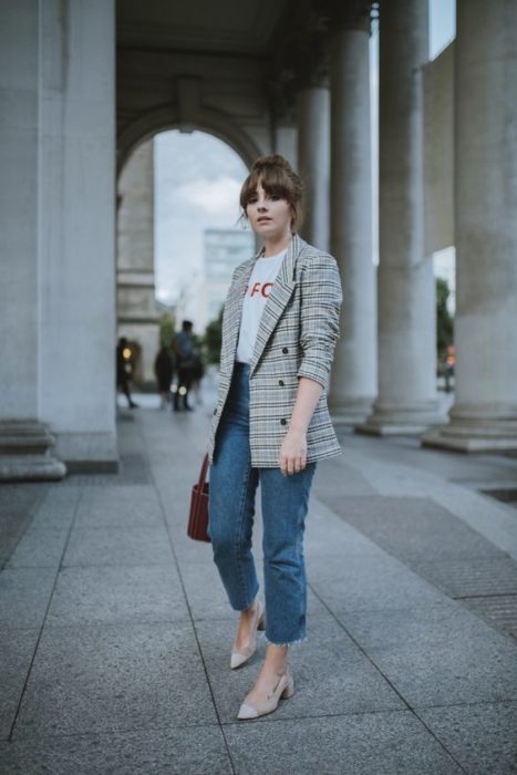 Mujer con abrigo café de cuadros viste jeans y zapatos beige con tacón cuadrado