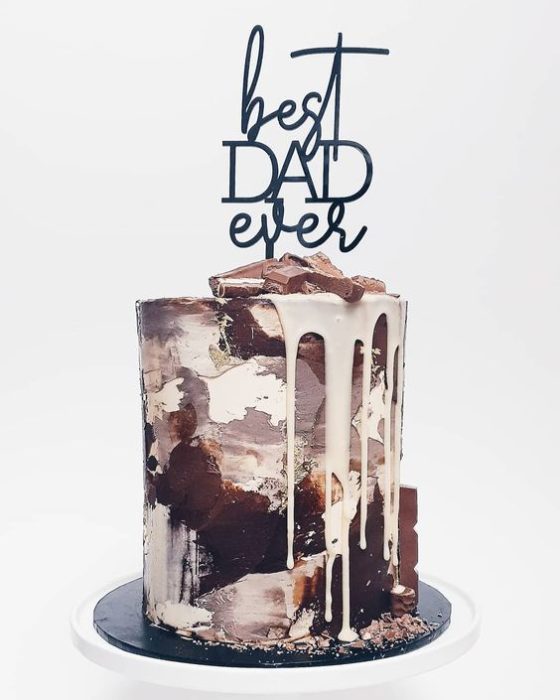 Pastel bañado en diferentes chocolates y decorado con letras abstractas que dicen feliz día del padre