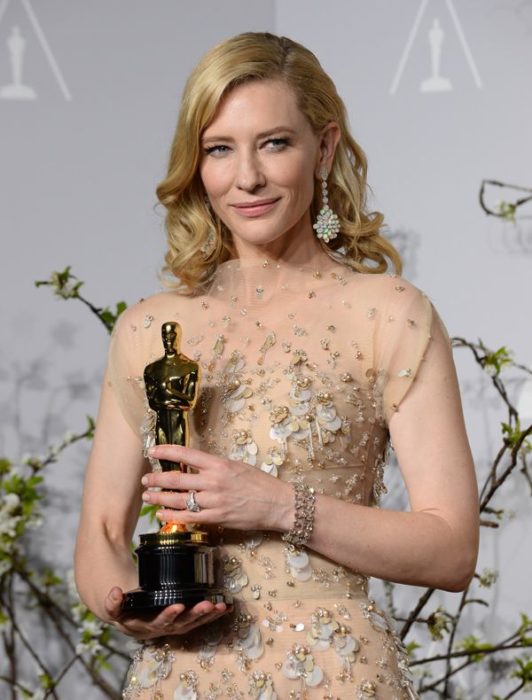 Cate Blanchett llevando un vestido dorado con transparencias sosteniendo una estatuilla al óscar