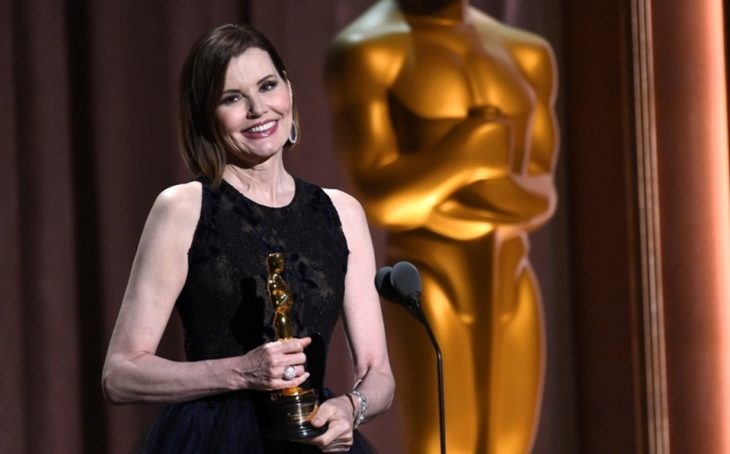 Geena Davis frente a un micrófono con vestido negro sosteniendo una estatuilla al Óscar