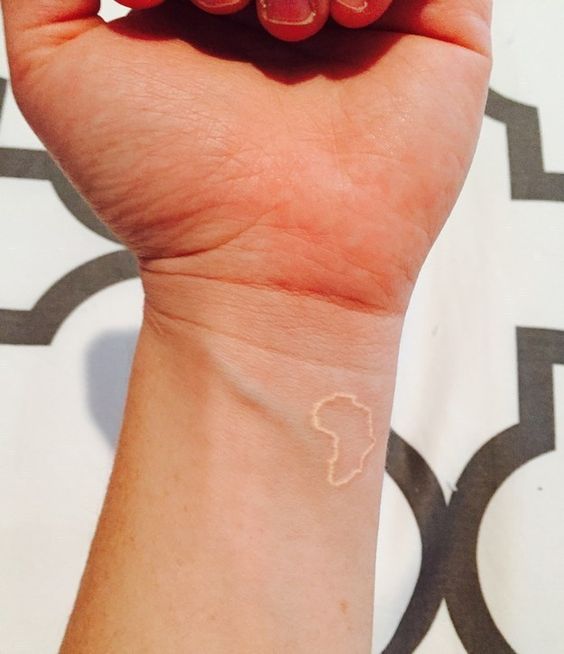 Tatuaje de África en la muñeca con tinta blanca