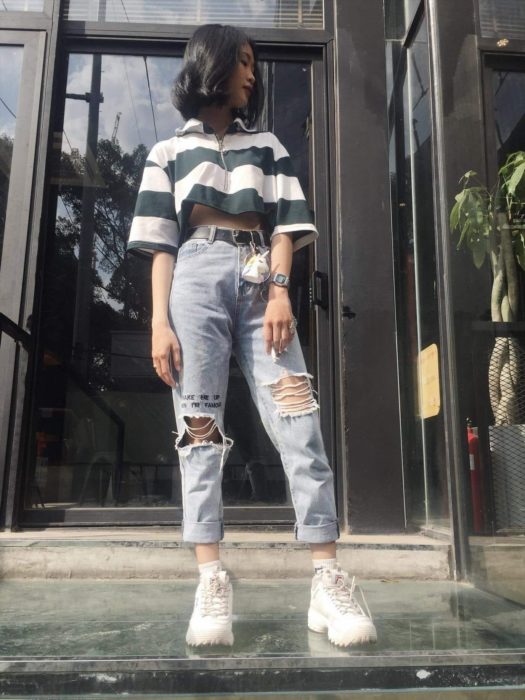 Chica con un outfit inspirado en Lara Jean que consiste en jeans, blusa ombliguera y tenis
