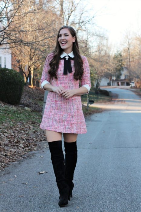Chica con un outfit inspirado en Lara Jean que incluye vestido de cuadros color rosa y botas negras altas
