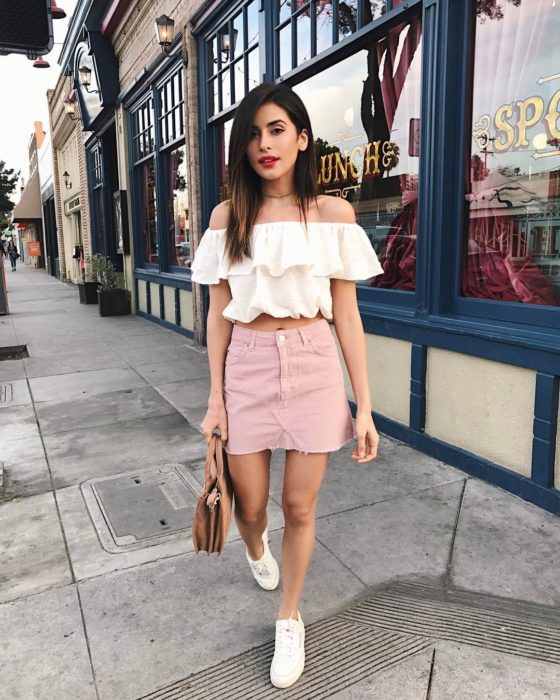Chica con un outfit inspirado en Lara Jean que incluye una falda rosa, tenis y blusa blanca