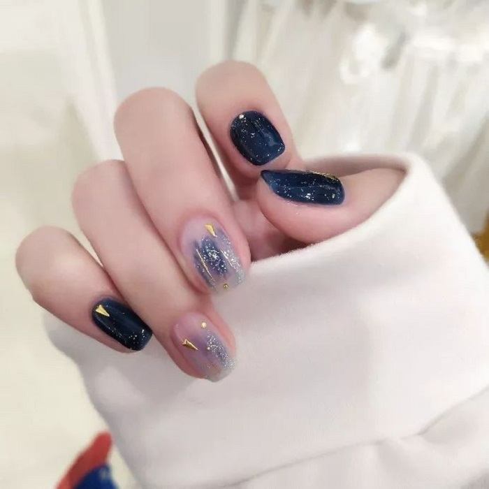 Diseño de manicura en tonos azul marino y cielo con detalles dorados