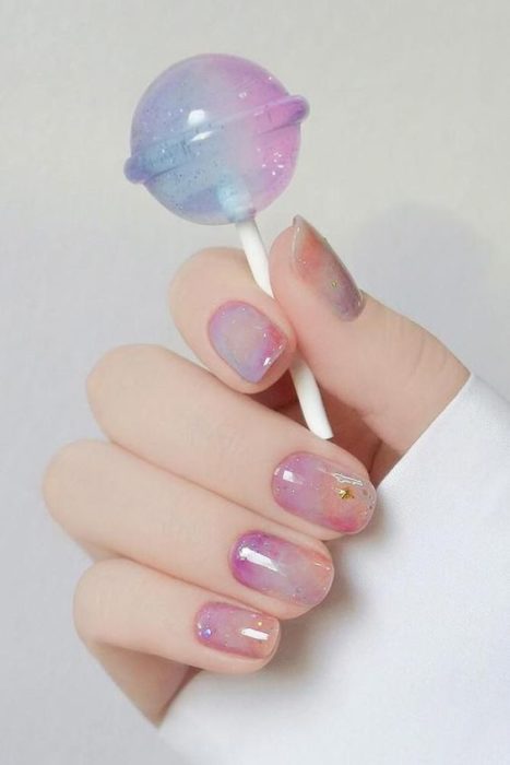 Diseño de manicura en tonos dulce o chicle con figuritas doradas
