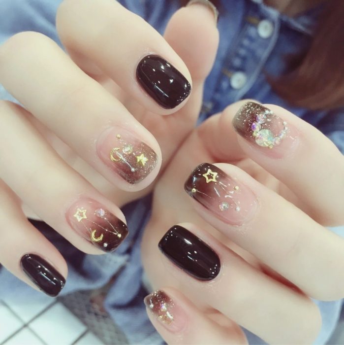 Diseño de manicura en tonos café con figuritas de estrellas