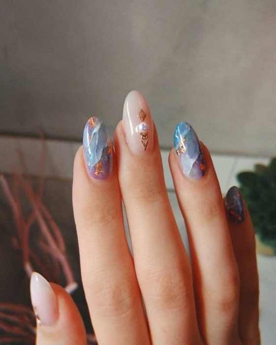 Diseño de manicura en tonos azules y rosas con detalles dorados