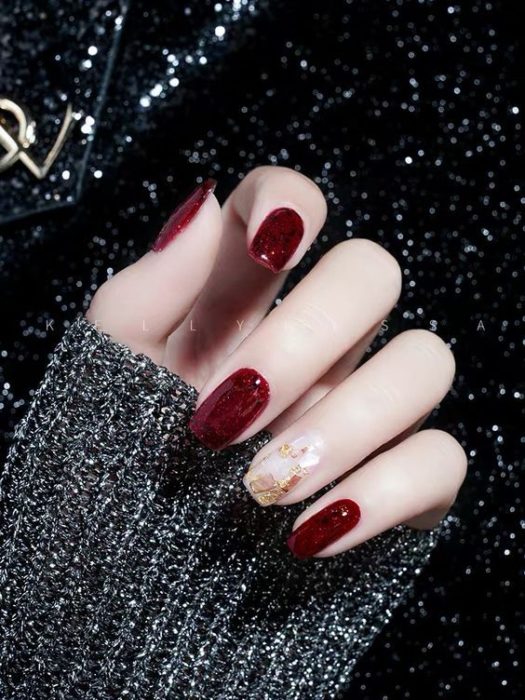 Diseño de manicura en tonos guinda y dorado