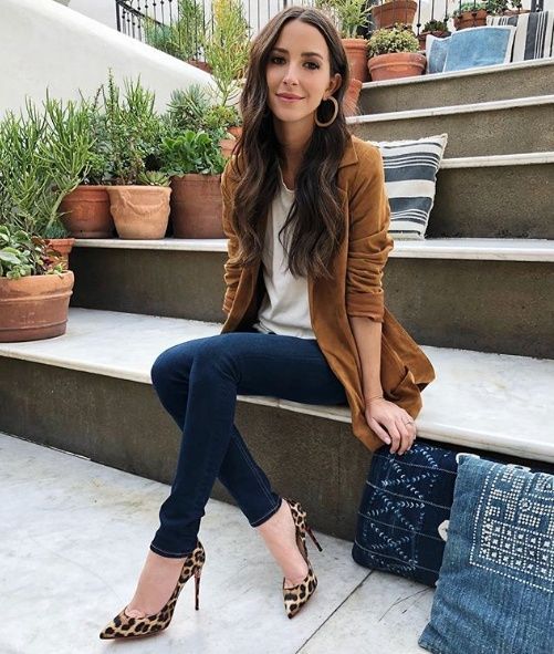 Chica de cabello largo sentada con saco color camel y zapatos animal print
