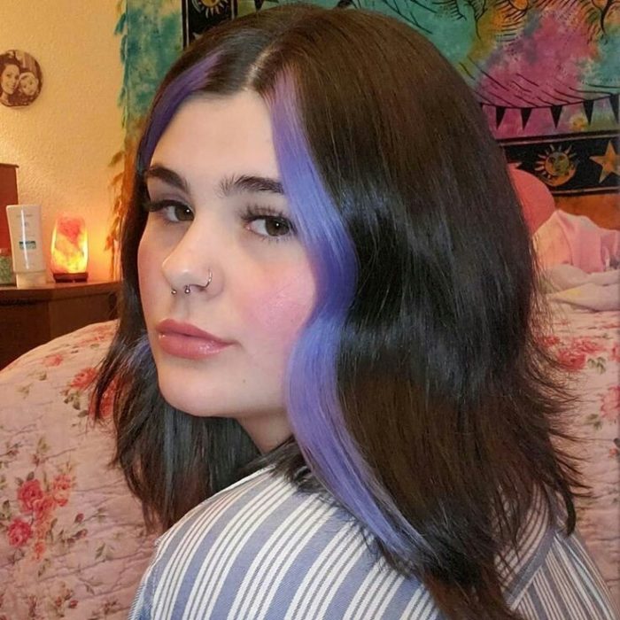 Chica con melena corta lleva mechones de cabello morados en la parte delantera