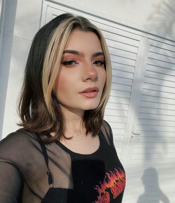 Chica con melena corta lleva mechones de cabello blancos en la parte delantera