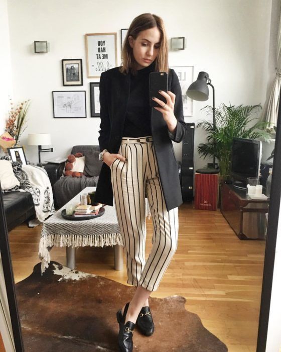 Chica usa saco y suéter negros con pantalón blanco con rayas negras