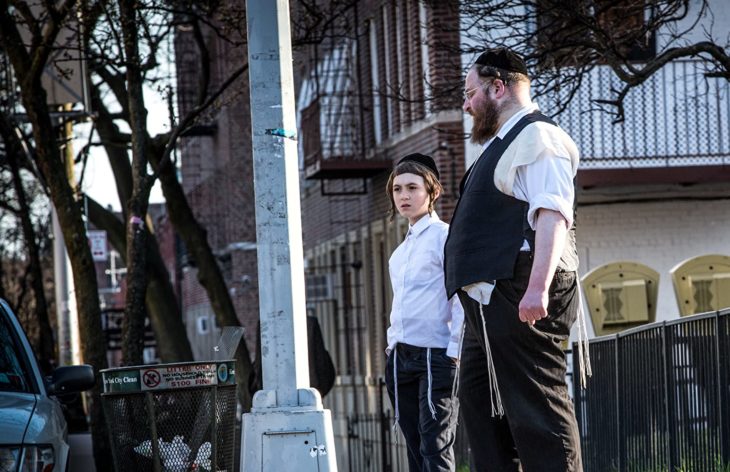 Padre e hijo judíos frente a una acera en la serie Menashe