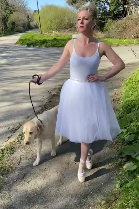 Mujer vestida de bailarina pasea con su perro