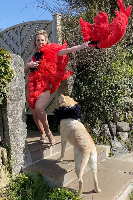 Mujer vestida de bailarina de can can mientras pasea con su perro