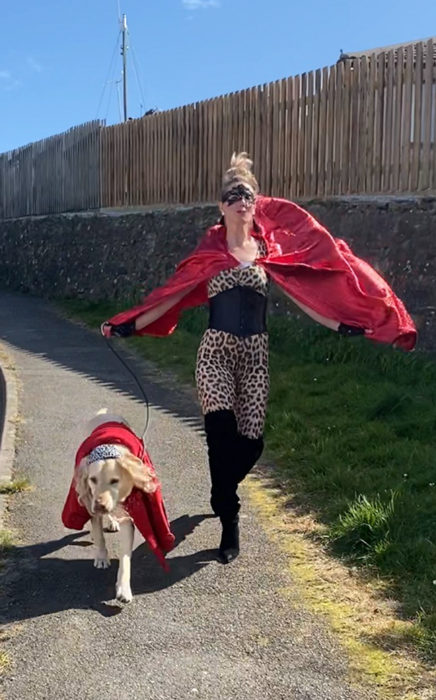 Mujer viste disfraz de superhéroe mientras pasea con su perro