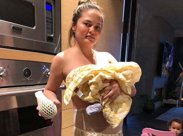 Chrissy Teigen cargando a su bebé recién nacido