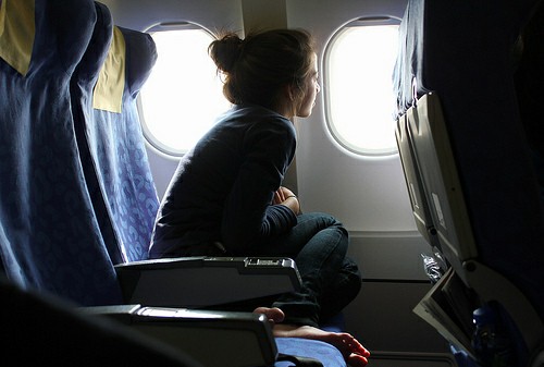 Chica sentada en un avión mirando por la ventana