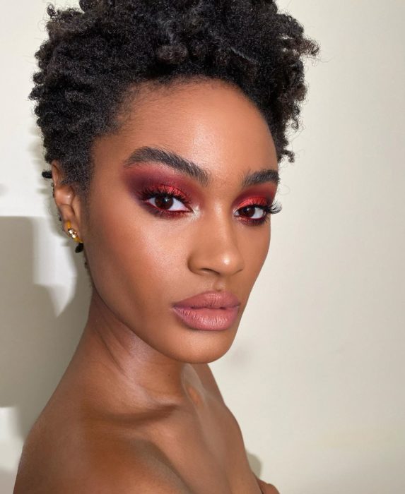 Modelo morena con cabello rizado y smokey eye rojo