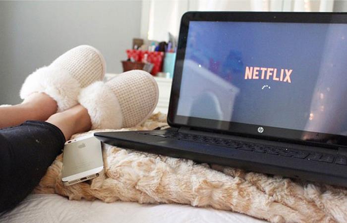 Chica recostada viendo Netflix en su laptop