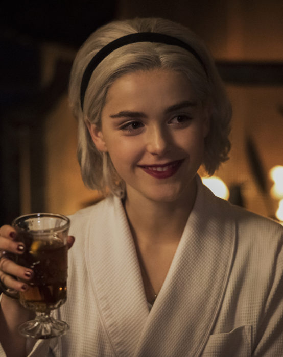 Personaje de las aventuras de Sabrina usando una diadema negra y bebiendo 