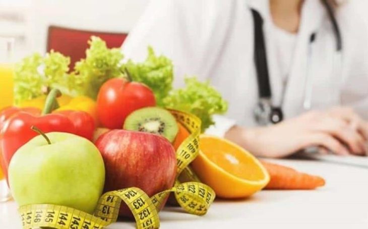Nutriologa sentada en su consultorio junto a una cesta de comida