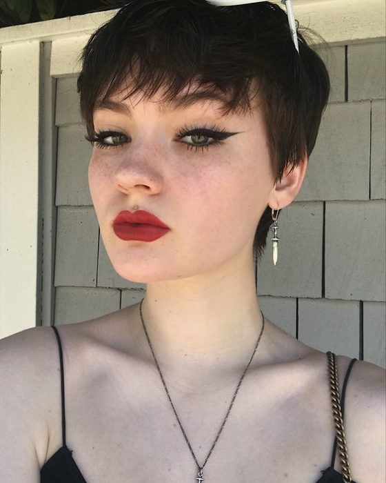 Chica blanca de ojos azules con delineado negro y labios rojos y cabello corto pixie