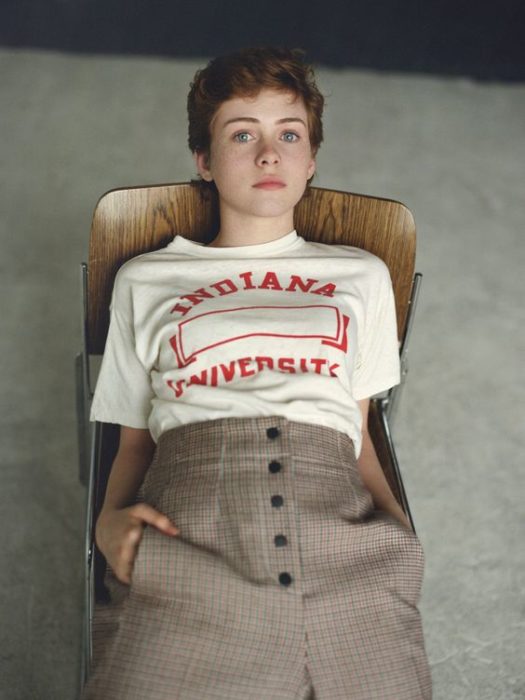 Sophia Lillis con cabello corto estilo pixie con falda gris y blusa blanca