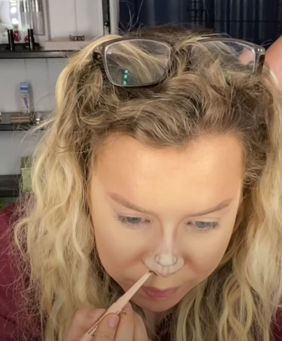 Mujer dibujando un pequeño rostro utilizando su nariz y frente