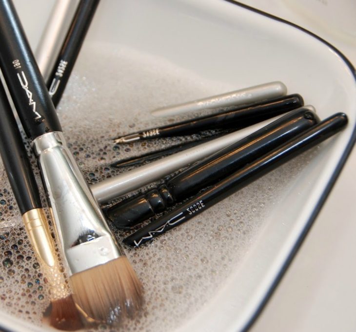 Brochas de maquillaje en un tazón con agua y jabón