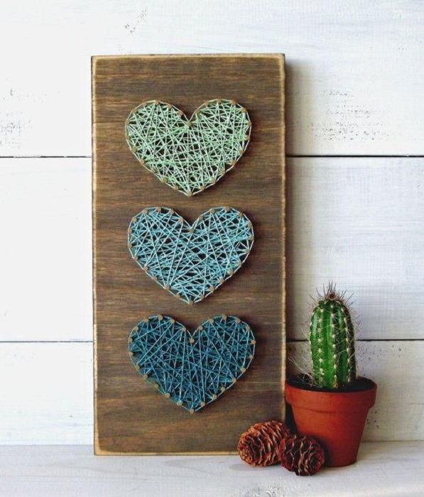 DIY de trozo de madera y clavos y estambre que forma corazones de diferentes colores