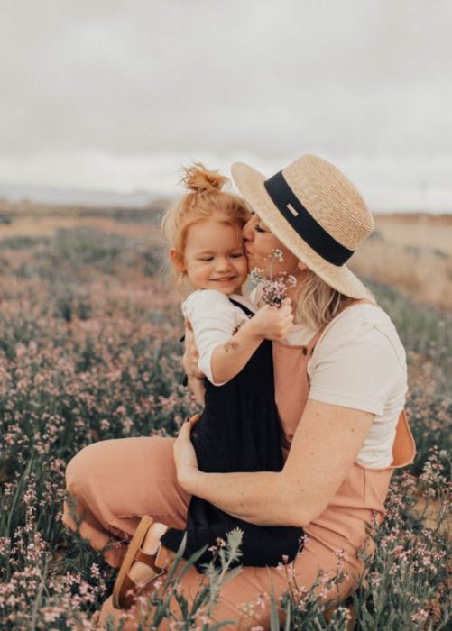 Madre besando a su hija en un campo 