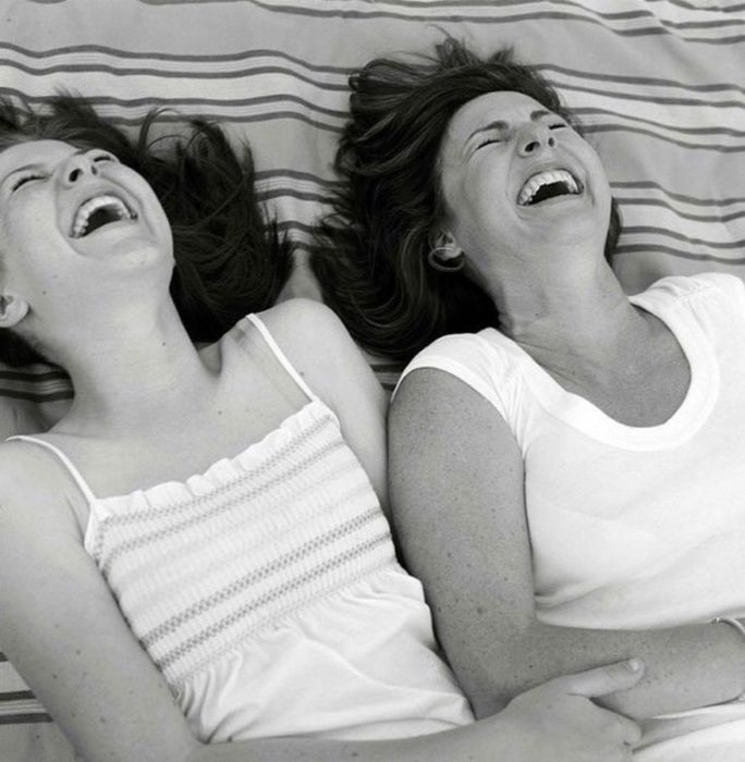 Madre e hija riendo en el pasto 