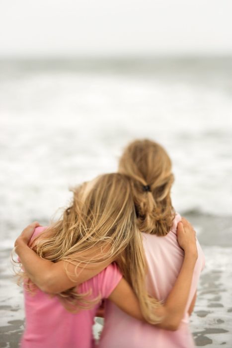 Madre e hija abrazadas mientras miran hacia el mar 
