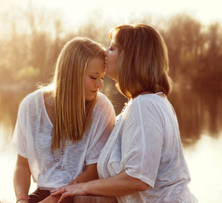 Madre besando a su hija en un campo 