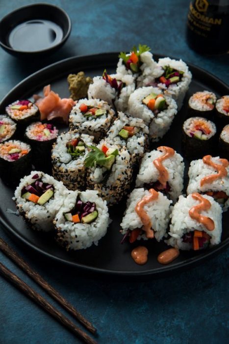 Sushi de pescado con aguacate en un plato negro grande
