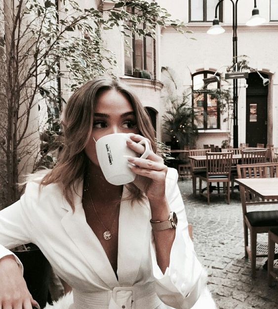 Chica con saco blanco bebe café