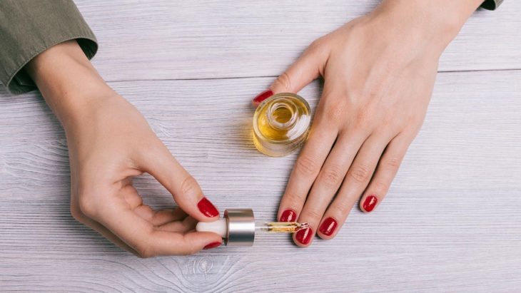 Chica aplicando aceite de cutícula