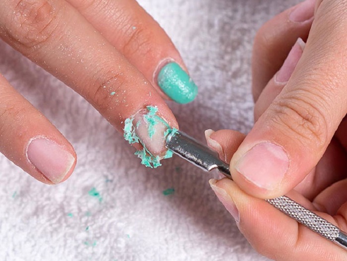 Chica retirando capa de gel de las uñas