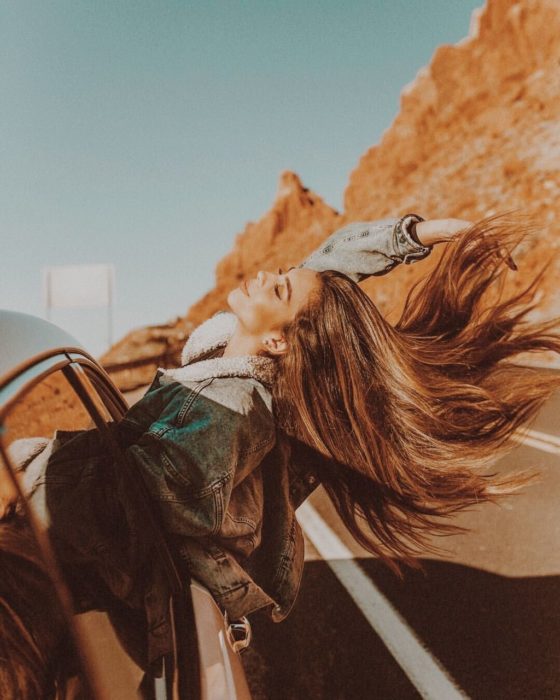 Chica en viaje por carretera asomándose por la ventana